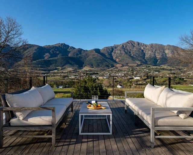 Luxurious mountain-view vineyard hotel nestled in scenic South African landscape, with elegant architecture and lush green surroundings at scenic location.