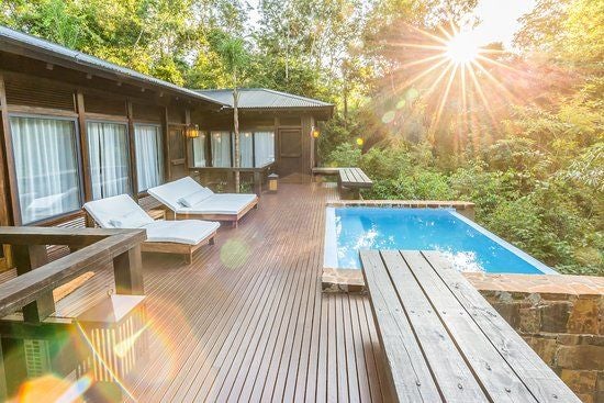 Elevated luxury villa nestled in lush Argentinian rainforest, featuring private deck and floor-to-ceiling windows at Awasi Iguazu resort