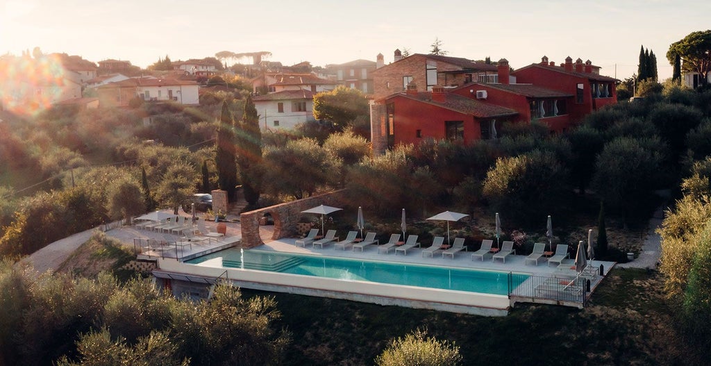 Elegant rustic Italian boutique hotel with stone exterior, lush green landscape, and terracotta roof nestled in scenic Tuscany countryside at golden hour