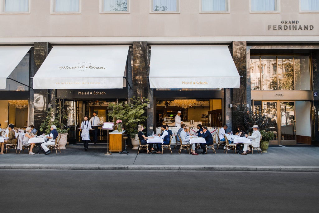 Elegant white exterior of Grand Ferdinand hotel in Vienna, featuring refined Art Nouveau architecture with ornate balconies and pristine marble facade