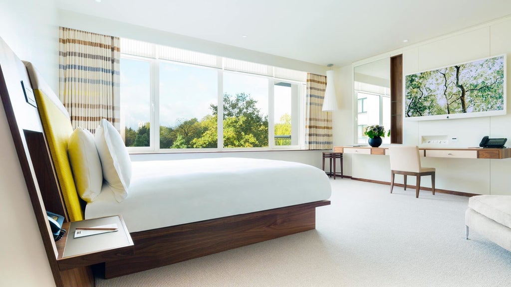 Luxurious COMO Suite with contemporary design, featuring plush white bedding, elegant neutral tones, and panoramic city views in London's metropolitan hotel.