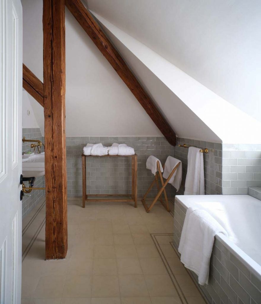 Rustic wooden interior of restored Transylvanian caretaker's house, featuring antique furniture, warm textiles, and soft candlelight against stone walls.