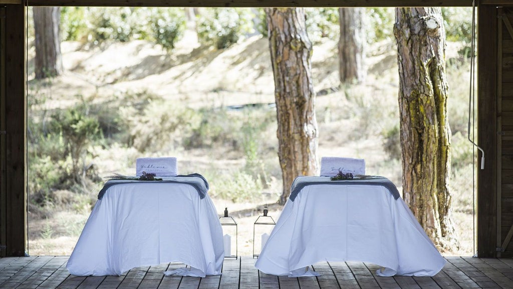 Luxurious minimalist hotel with wooden structures overlooking sand dunes and pristine coastal landscape in Comporta, Portugal, featuring modern architecture and natural elements.