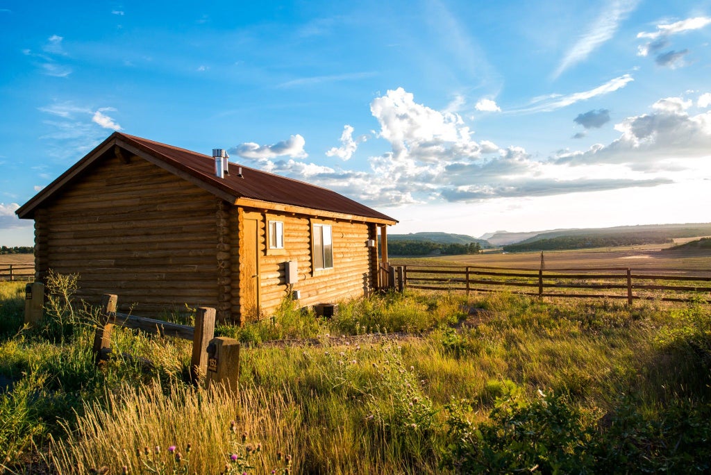 Rustic wooden cabin bedroom with plush king bed, large window overlooking scenic mountain landscape at Zion scenset Ranch retreat