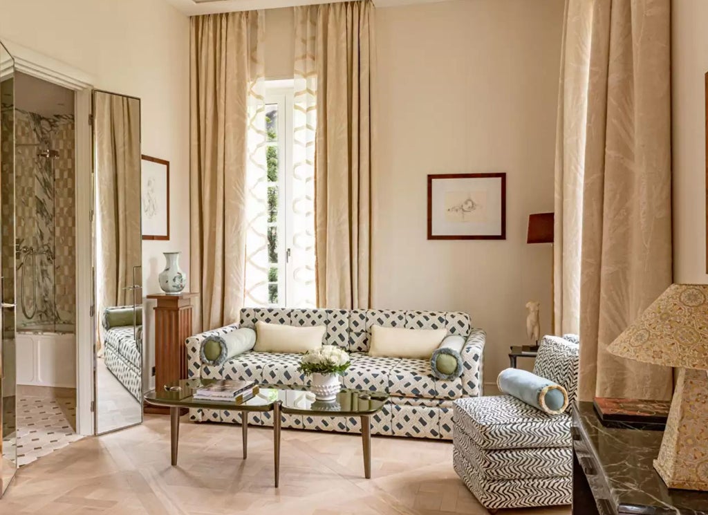 Opulent hotel room with emerald walls, ornate gold mirrors, crystal chandelier, Louis XVI furniture and plush striped fabric headboard