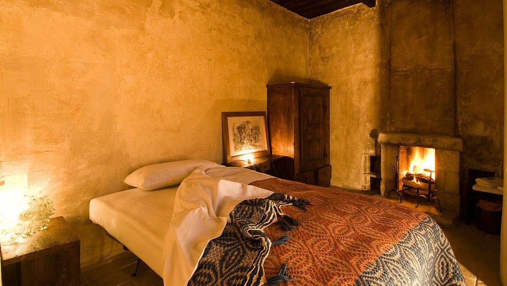 Rustic stone-walled hotel room with lake view, featuring antique wooden furnishings, soft linens, and warm traditional Italian design elements