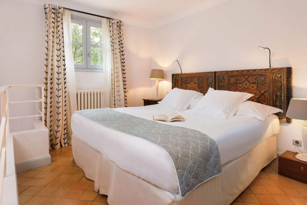 Elegant Provençal-style hotel room with stone walls, antique furnishings, soft natural light, and refined rustic charm at a historic French monastery