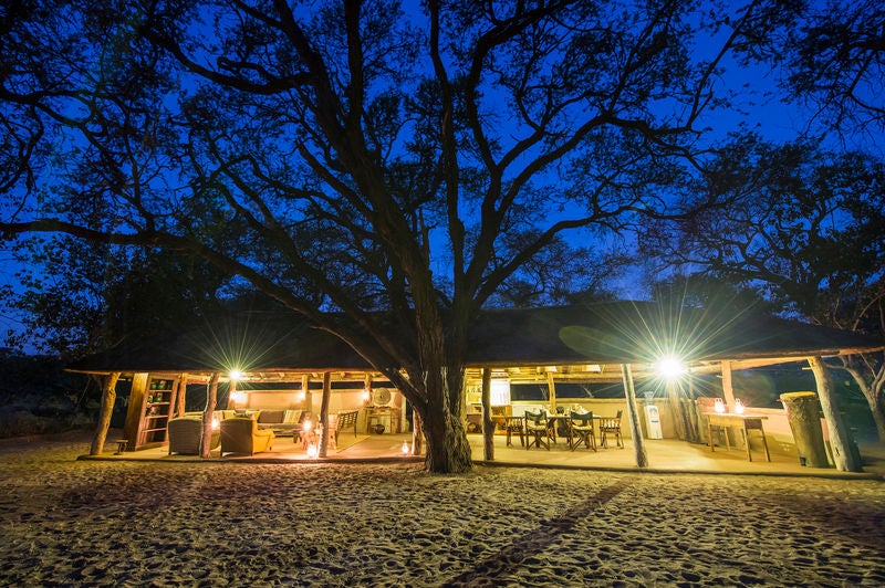 Luxurious safari tent overlooking Botswana wetlands, featuring private deck, canvas walls and thatched roof amid natural savanna