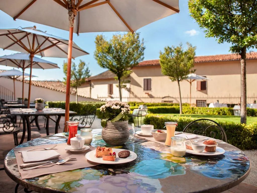 Historic stone facade of elegant Palazzo Seneca hotel nestled in Umbrian hillside, showcasing Renaissance architectural details and warm terracotta tones