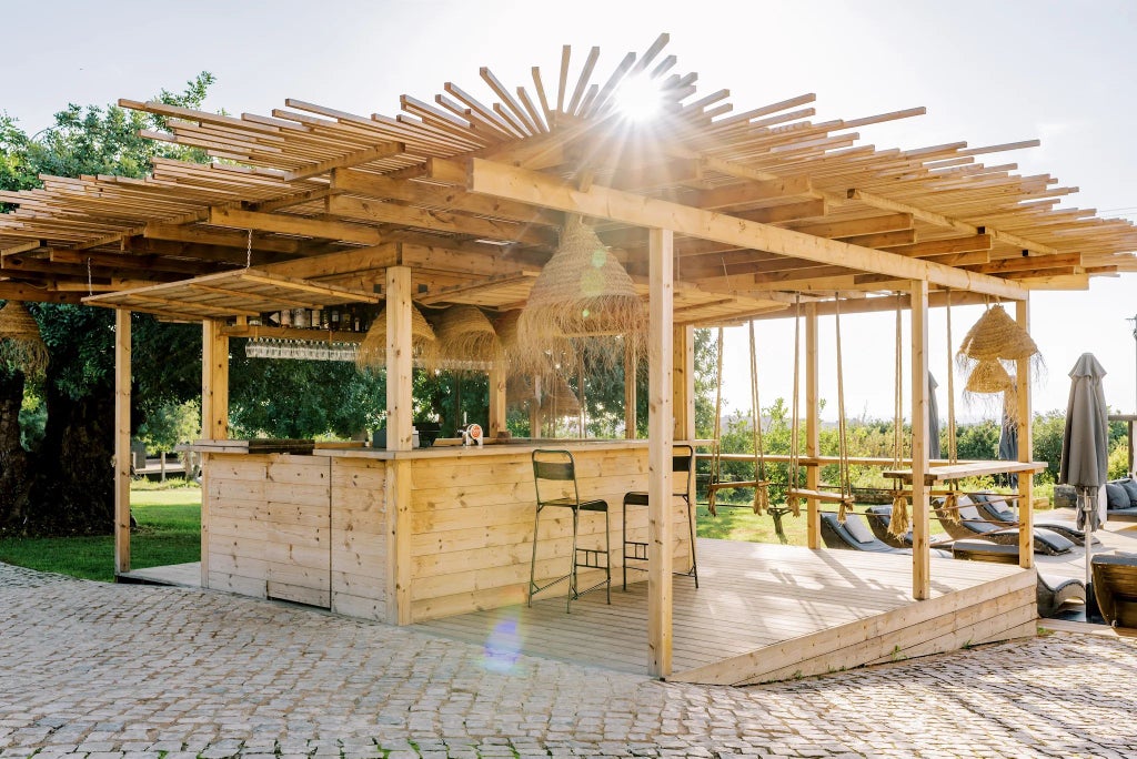 Rustic Portuguese wooden terrace of luxurious Hotel Conversas de Alpendre with panoramic mountain view, warm sunlight, and traditional architectural details