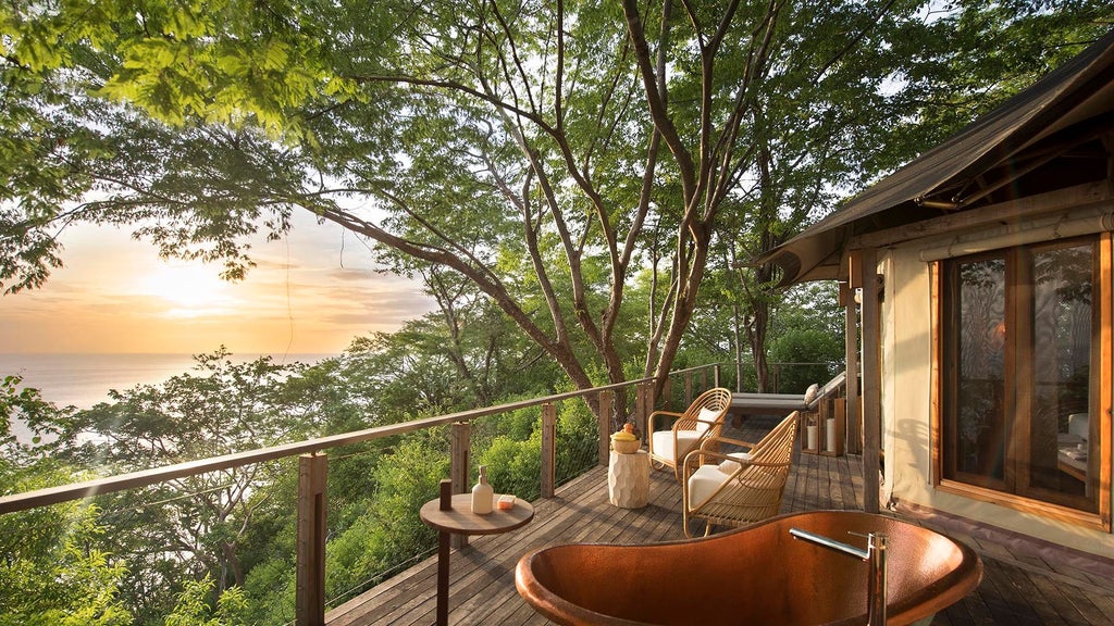 Luxurious eco-lodge tent suite nestled in Costa Rica's lush jungle, featuring a private deck overlooking the Pacific Ocean at sunset