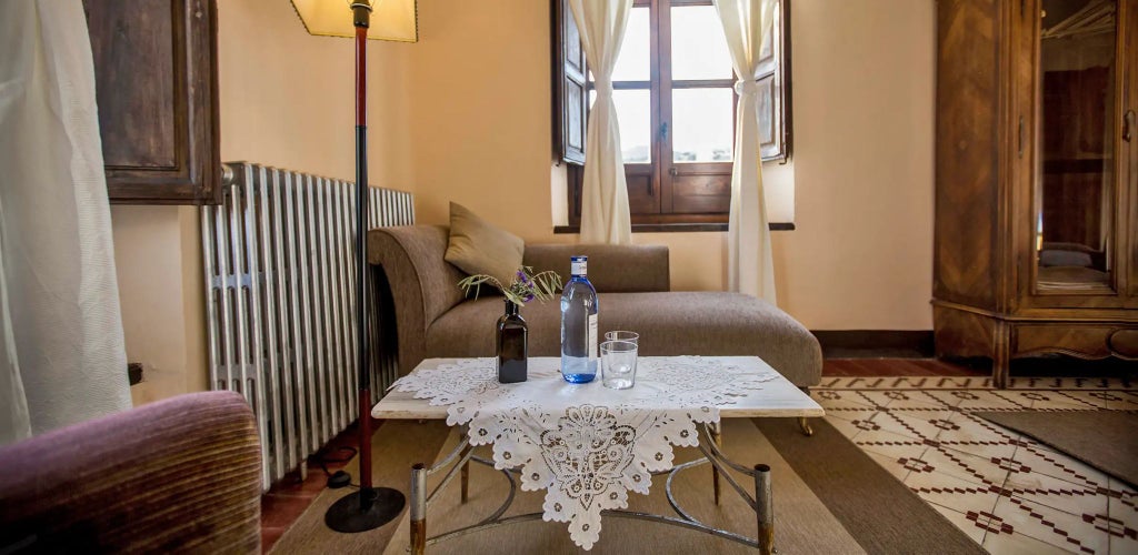 Luxurious Spanish stone tower bedroom at Cortijo del Marqués, featuring elegant rustic decor, arched windows, and warm natural light filtering across traditional architectural elements