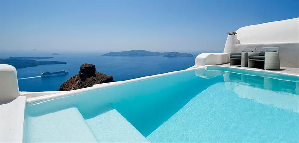 Whitewashed luxury cave hotel built into Santorini cliffside, featuring curved architecture and private infinity pools overlooking the Aegean Sea