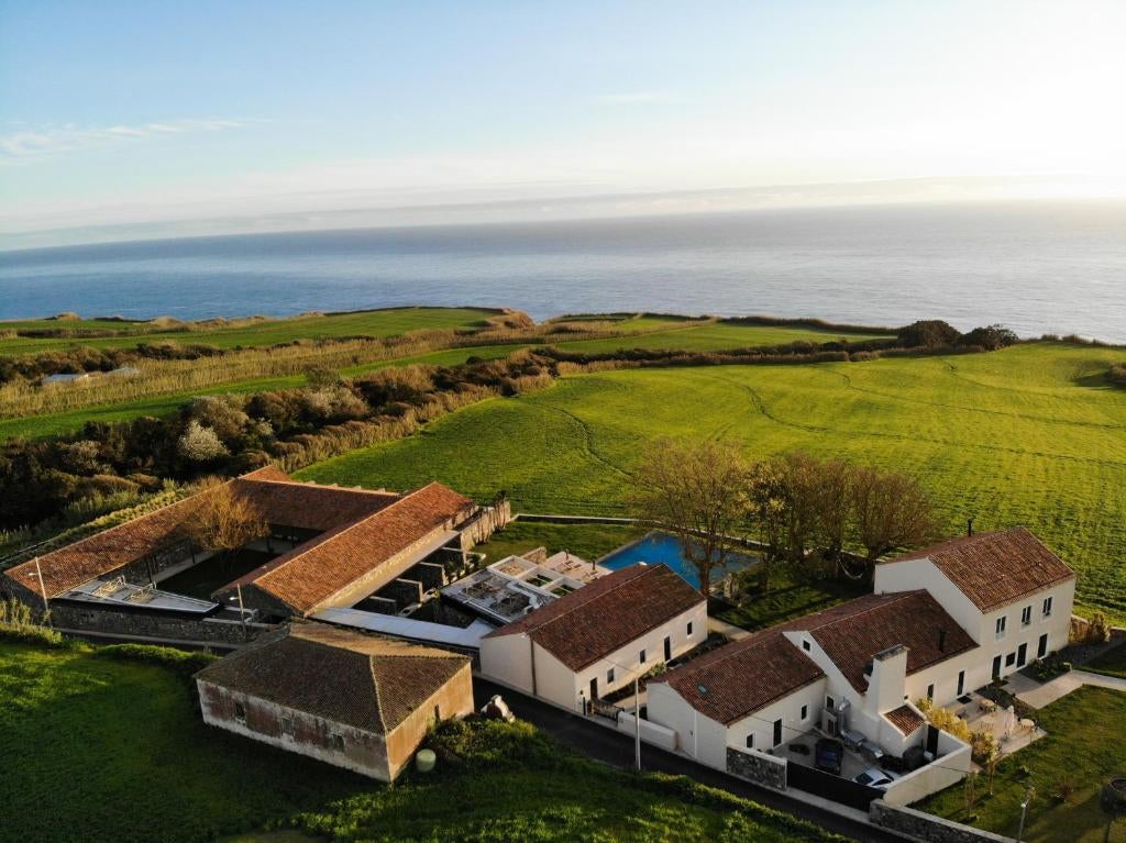 Modern glass-fronted luxury hotel nestled in lush Azorean landscape, featuring sleek architecture and infinity pool overlooking ocean views