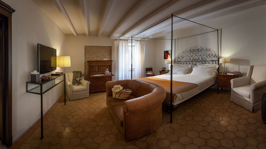 Elegant Italian suite at Palazzo Seneca with plush white bedding, ornate wooden furnishings, and soft warm lighting highlighting traditional Umbrian architectural details