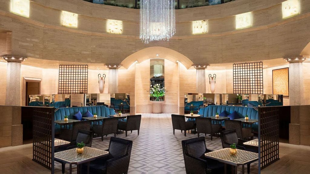 Elegant marble lobby of Park Hyatt Milan featuring grand chandeliers, ornate columns, and plush seating in warm beige and gold tones