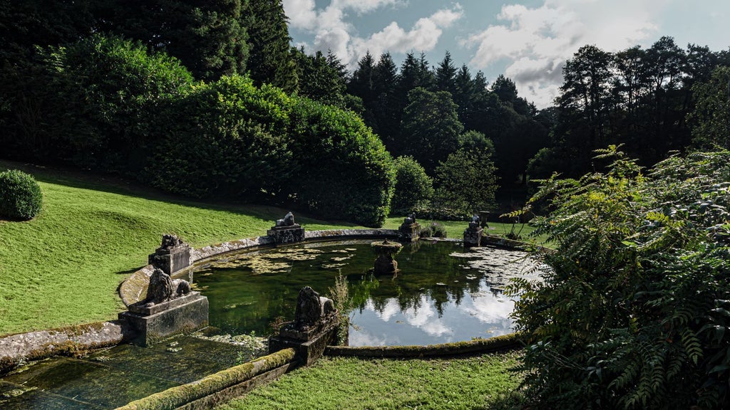 Luxurious countryside hotel with modern architectural design, nestled in lush green landscape, featuring contemporary glass and stone exterior at twilight