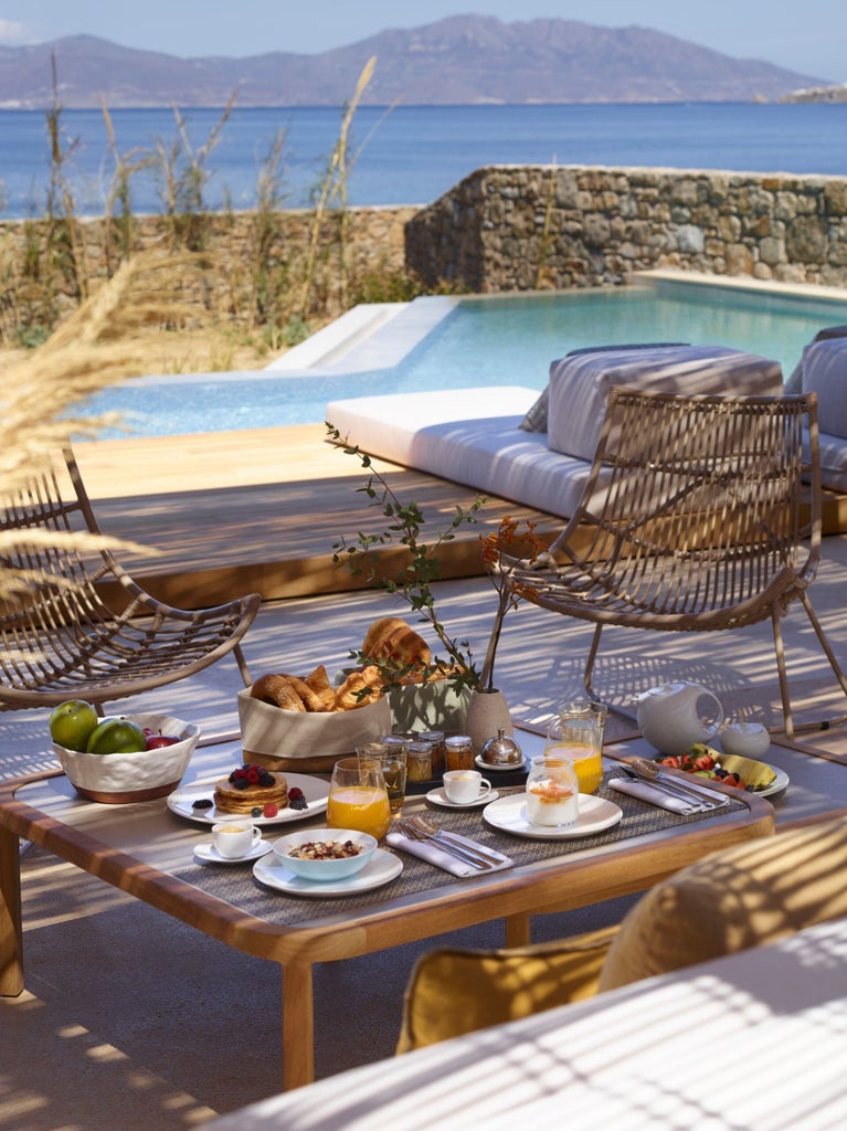 Elegant white villa with private infinity pool overlooking the Aegean Sea at sunset, featuring minimalist Greek architecture and sea views