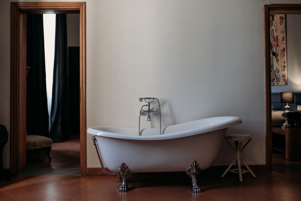 Elegant Tuscan-style king room with ornate vintage furnishings, soft neutral palette, and French doors opening to a charming balcony overlooking Florence.