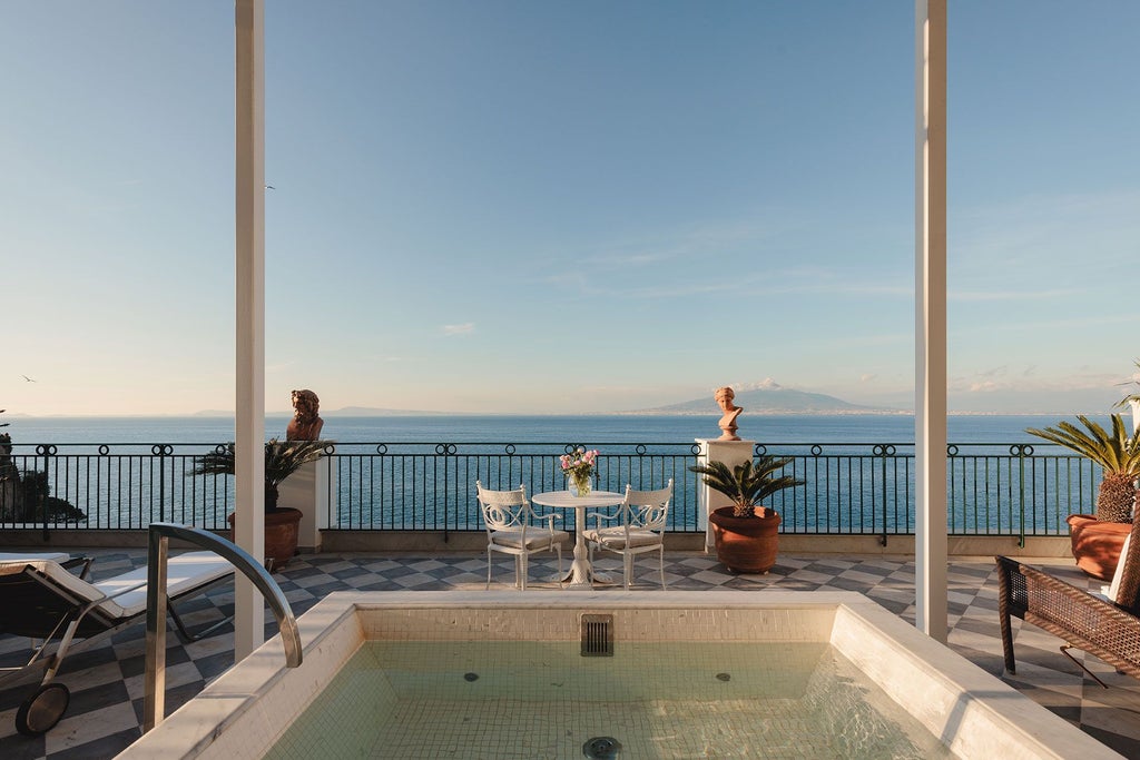 Opulent suite at Bellevue Syrene overlooking Sorrento's coastline, featuring elegant marble floors, antique furnishings, and panoramic Mediterranean views