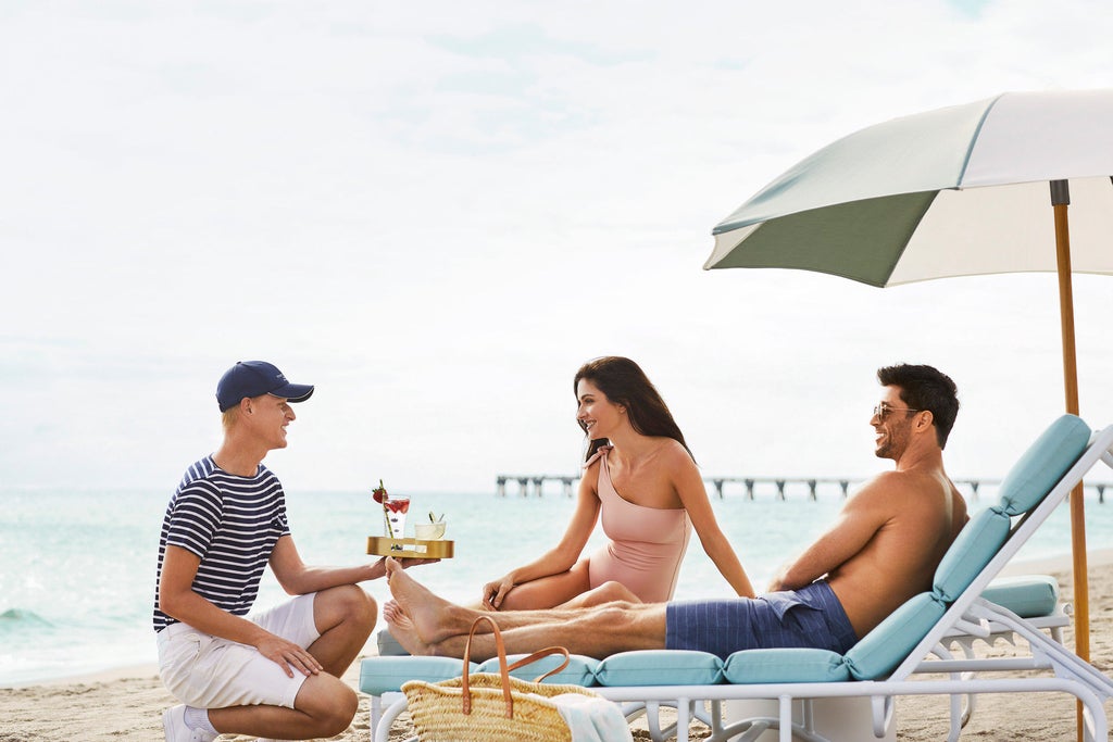 Elegant beachfront hotel with palm-lined pool area, white cabanas, and pristine private beach against turquoise Atlantic Ocean waters