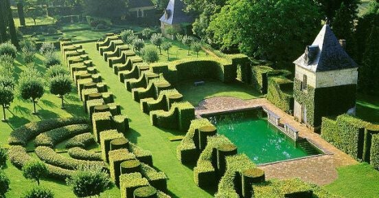 Grand 17th-century French château with elegant limestone facade, symmetrical windows, and manicured gardens set against blue summer sky