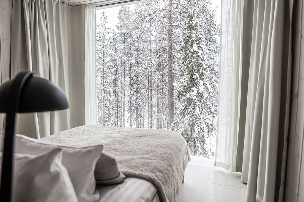 Luxurious wooden Nordic cabin nestled in snowy forest with panoramic glass walls, showcasing modern Arctic accommodation design in Finnish Lapland