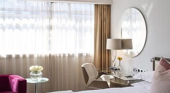 Elegant cosy room with plush white bedding, warm wooden furnishings, soft neutral tones, and contemporary design at boutique hotel in United Kingdom