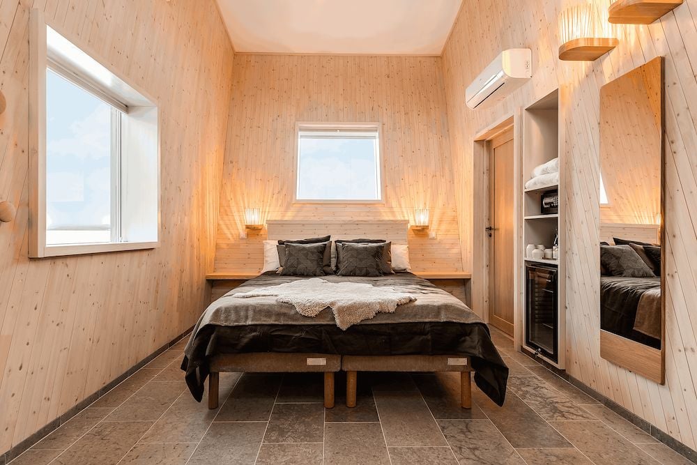 Minimalist wooden cabin interior with large windows overlooking frozen river, featuring sleek Nordic design and warm, minimalist Nordic decor in Arctic landscape
