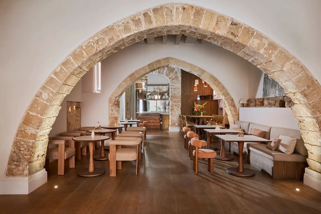 Elegant stone facade of boutique hotel in Palma de Mallorca, warm Mediterranean sunlight casting soft shadows on traditional architectural details