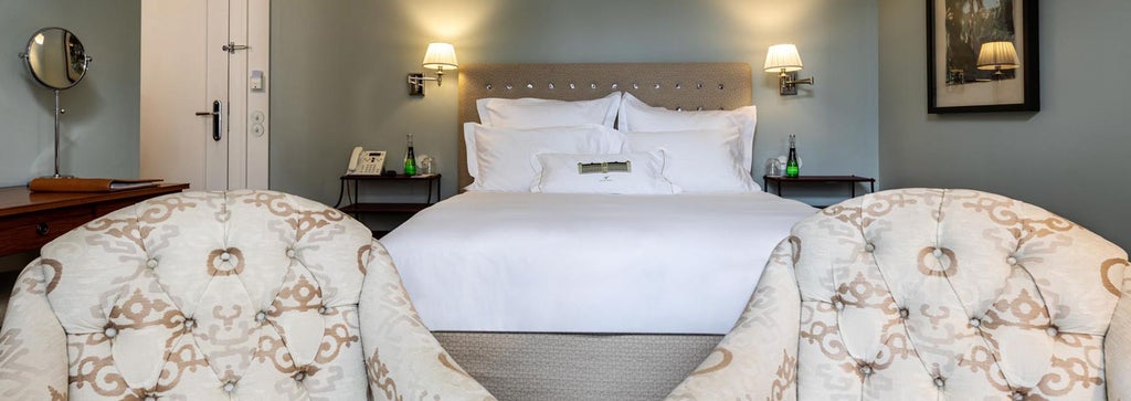 Elegant marble-clad Art Nouveau hotel room with plush white bedding, crystal chandelier, and ornate gilded furnishings at Vidago Palace in Portugal