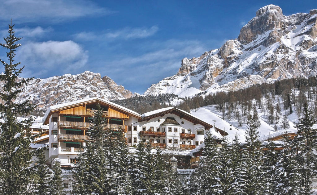 Luxurious mountain resort Rosa Alpina nestled in Italian Dolomites, featuring stone and timber facade with flower-adorned balconies