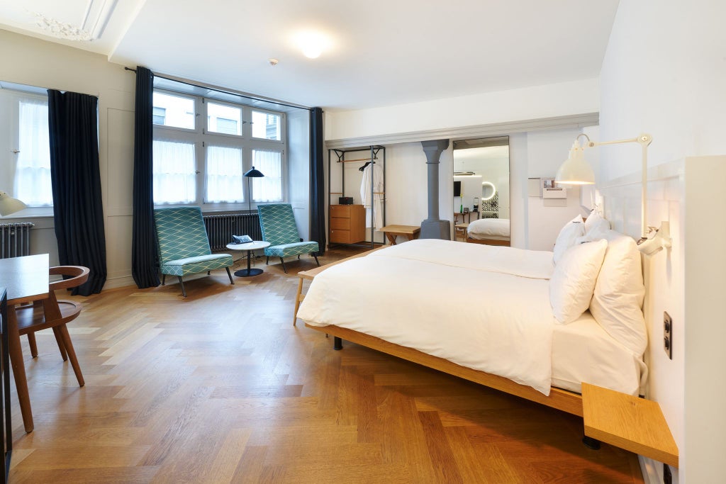 Elegant Swiss double room with vintage wooden furnishings, soft neutral color palette, and large window overlooking historic streetscape at scenset Marktgasse Hotel