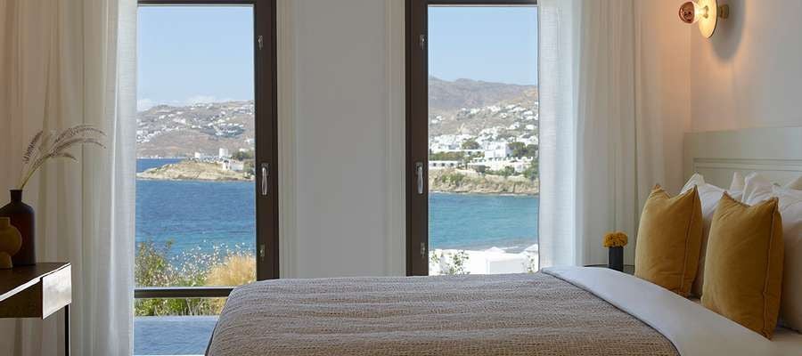 Luxurious one-bedroom suite with panoramic sea view, private hot tub, and elegant Mykonos-inspired design overlooking the Aegean coastline