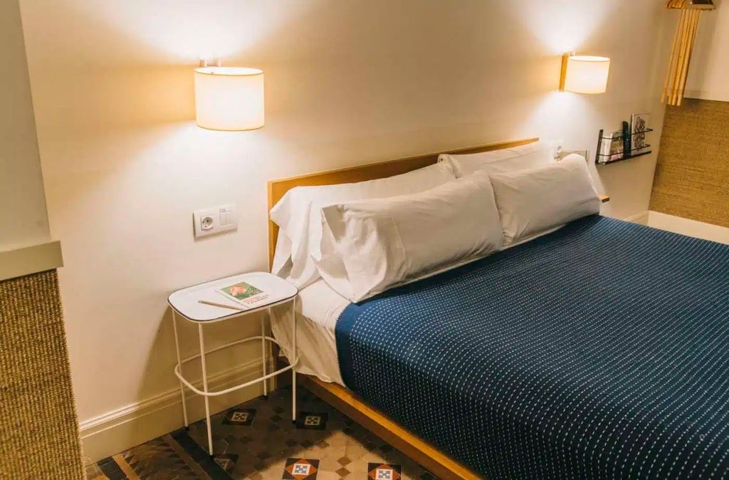 Minimalist hotel room at Casa Bonay with warm wooden floors, crisp white linens, and large windows overlooking Barcelona's urban landscape