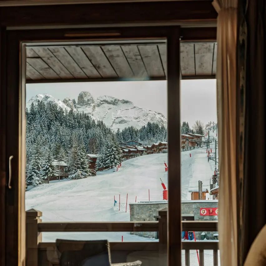 Luxurious alpine ski chalet-style hotel nestled in snowy mountain landscape with modern wooden exterior and panoramic mountain views at scenset Hotel