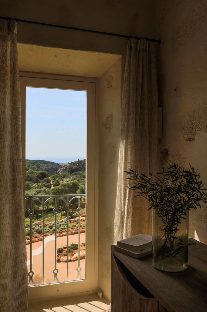 Mediterranean luxury boutique hotel with pristine white facade, elegant stone arches, and lush green gardens under bright Spanish sun