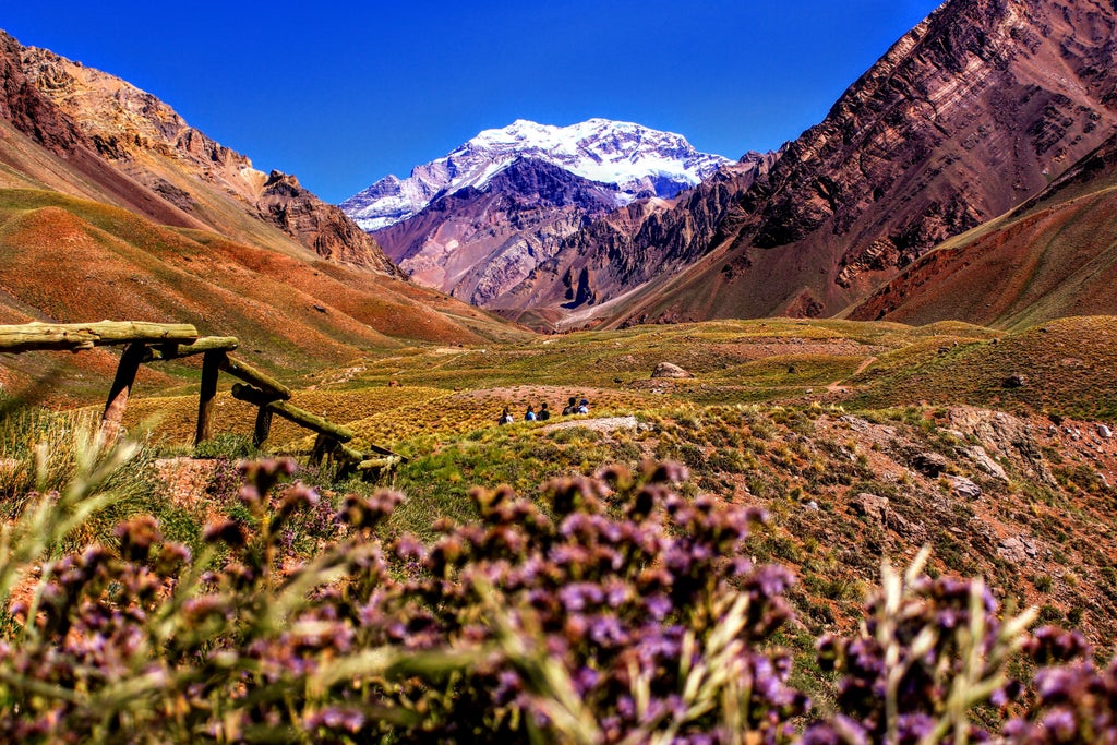 Rolling vineyards at sunset with Andes Mountains backdrop, luxury winery estate nestled among autumn-colored vines in Mendoza valley