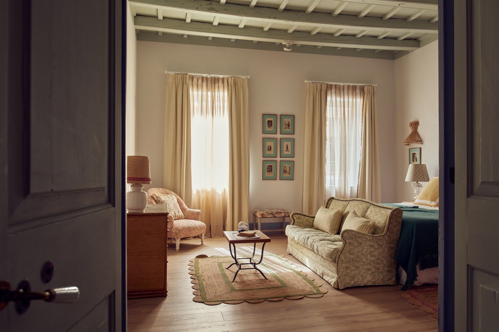 Historic Spanish boutique hotel with whitewashed facade featuring elegant arched windows, traditional shutters, and lush potted plants