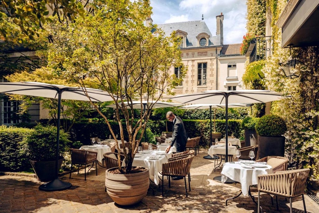 Historic Parisian hotel facade with ivy-covered walls, elegant stone architecture and ornate iron gates, nestled in Place des Vosges square