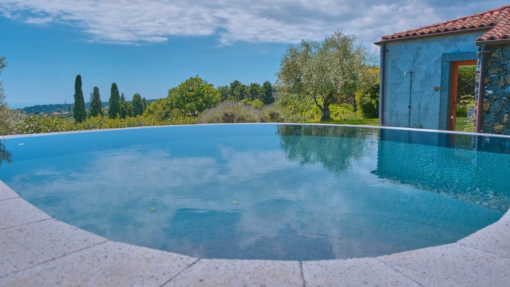 Scenic infinity pool overlooking lush Sicilian landscape at luxury boutique hotel, with elegant stone terrace and Mount Etna in background