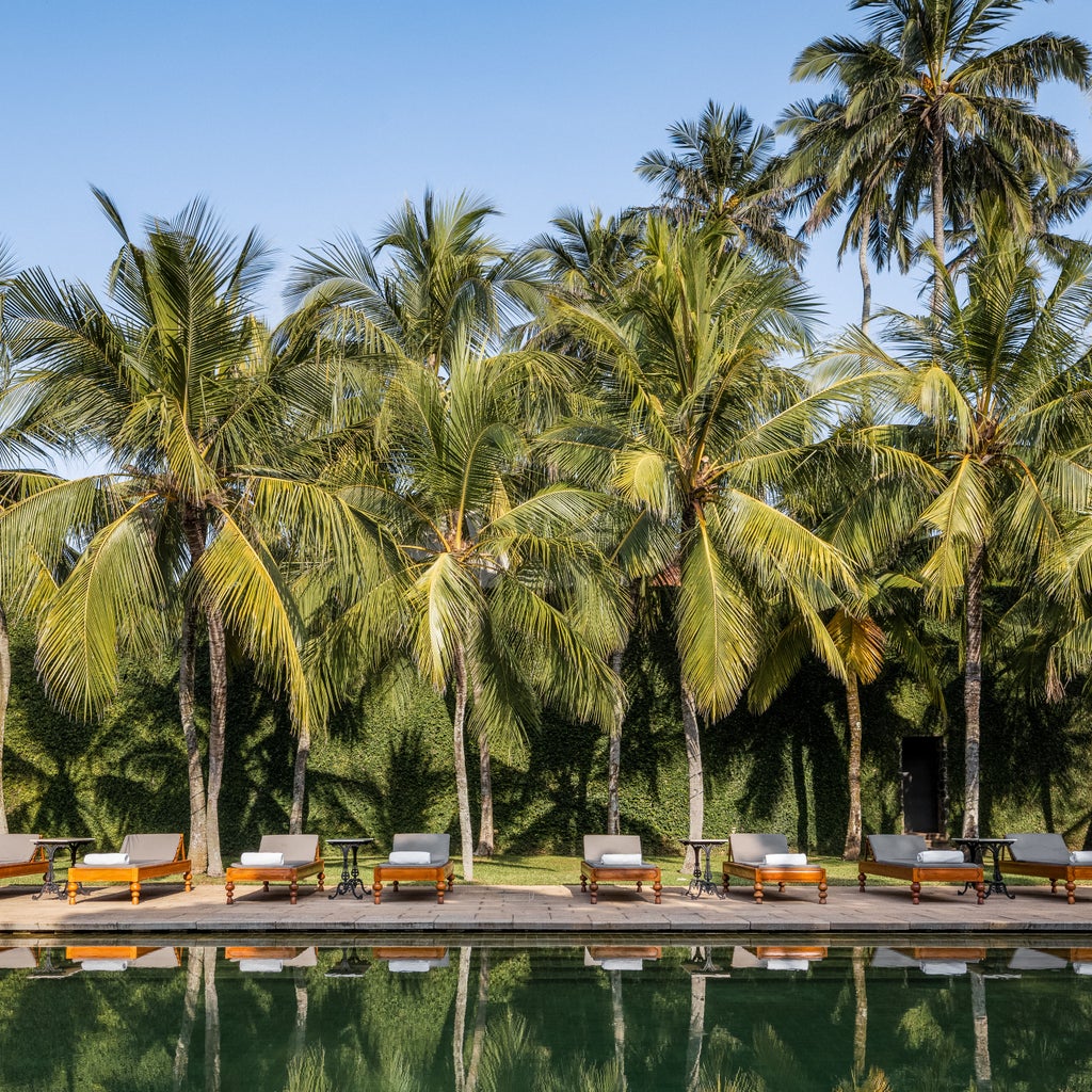 Historic luxury hotel Amangalla's colonial-era facade with tall white columns, wooden shutters and tropical foliage in Galle, Sri Lanka