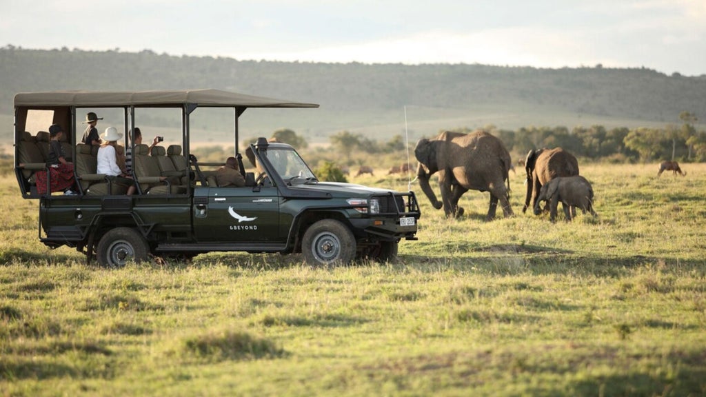 Luxury safari tent at andBeyond Kichwa Tembo camp overlooking vast Kenyan savanna with acacia trees and distant wildlife silhouettes at golden hour