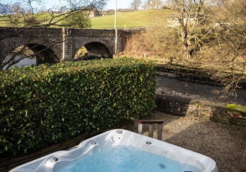 Elegant boutique hotel room with plush white bedding, modern minimalist decor, and large windows overlooking scenic countryside at Yorebridge House