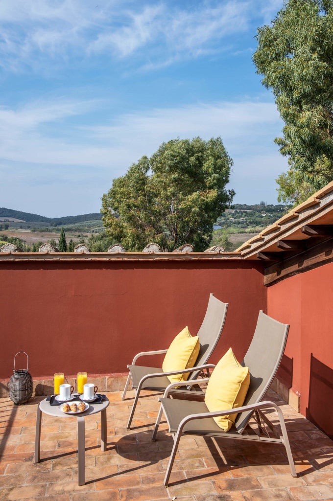 Elegant Tuscan-style deluxe terrace room with rustic stone walls, plush white bedding, and panoramic countryside views at Locanda Rossa