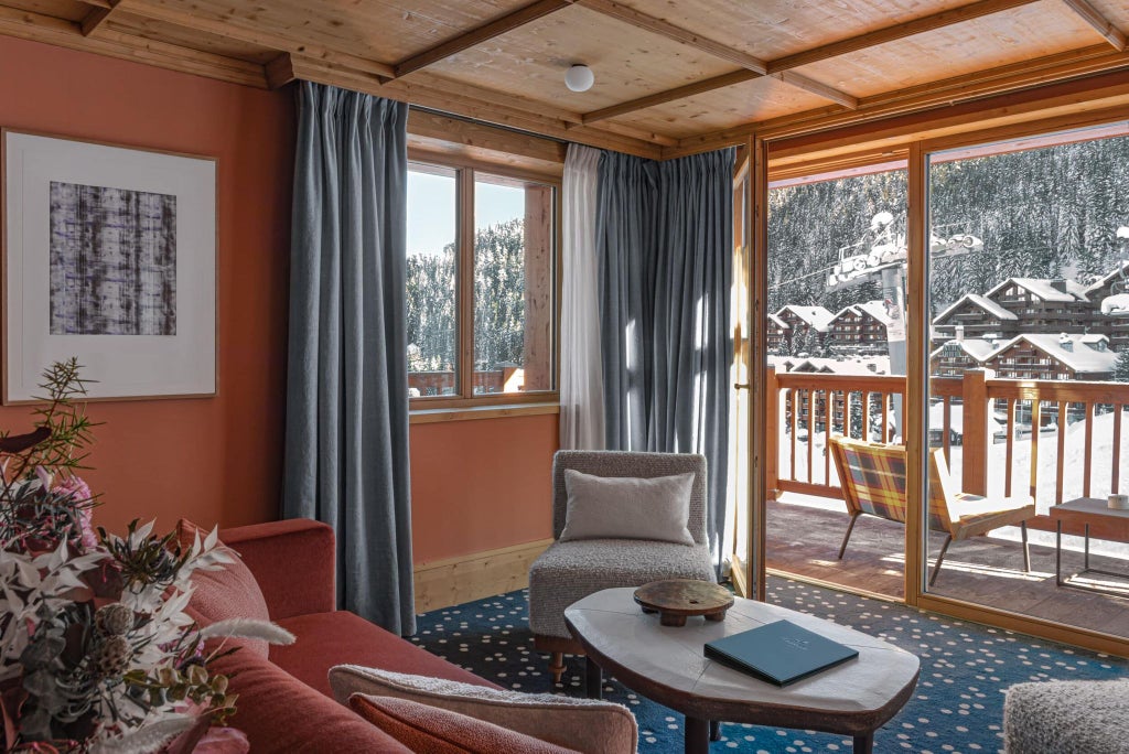 Luxurious superior suite at Le Coucou Méribel, featuring alpine-inspired modern decor, plush white bedding, and expansive mountain view windows in French Alps