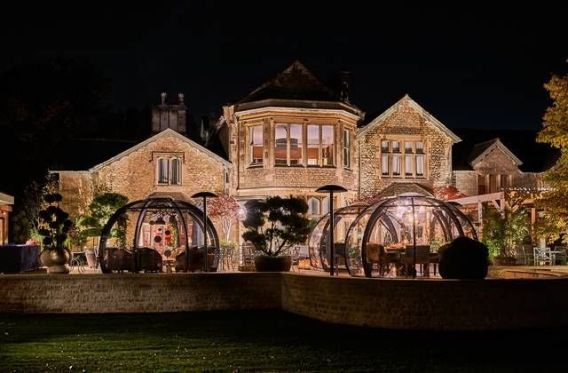 Luxurious spa hotel facade with modern architecture, nestled in lush UK countryside, featuring elegant stone exterior and manicured landscaping at dusk