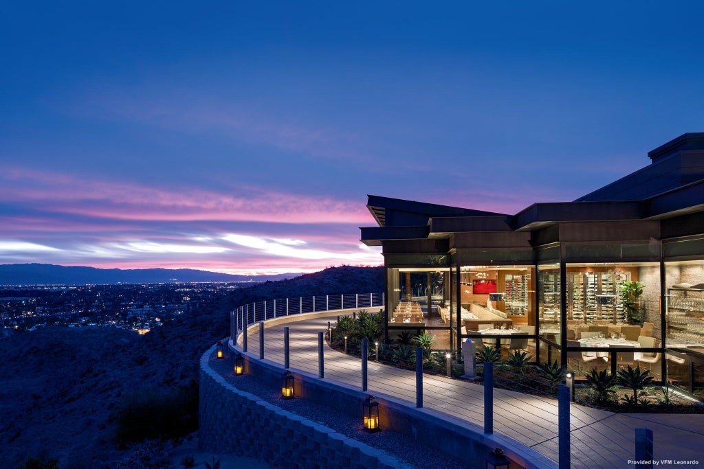 Luxurious desert resort with modern architecture nestled in palm-lined hills, featuring infinity pools and panoramic valley views