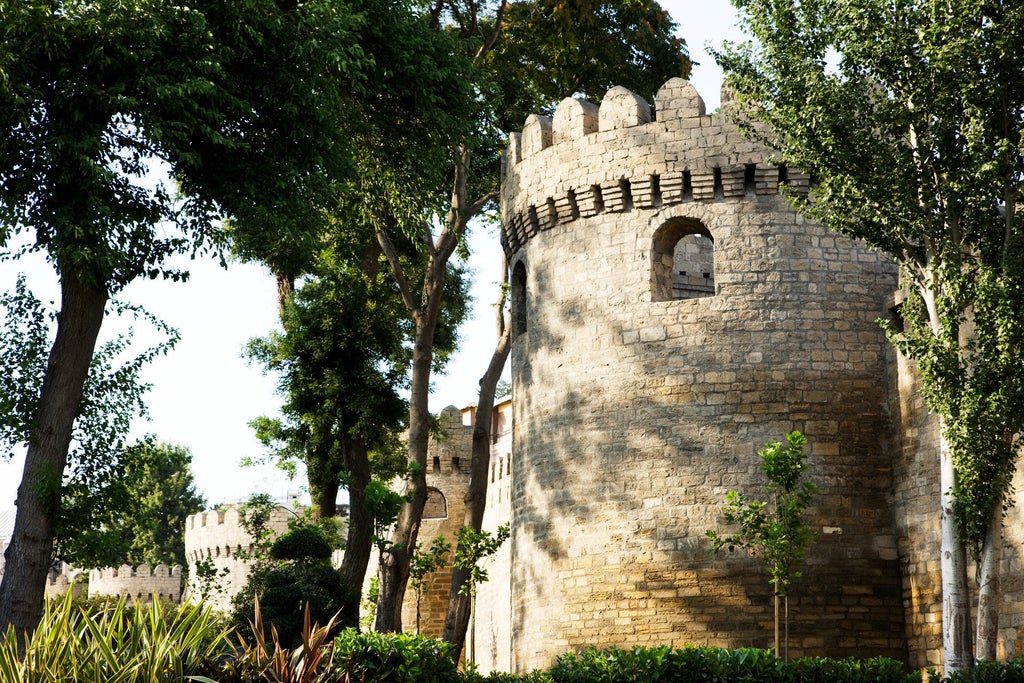 Opulent beige limestone hotel tower with French Beaux-Arts architecture, ornate balconies and grand arched windows overlooking the Caspian Sea