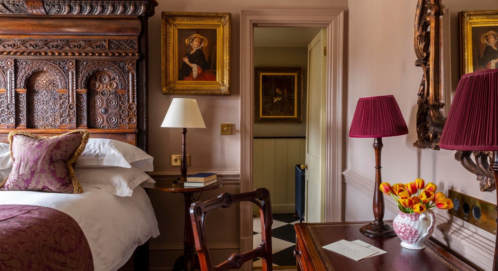 Elegant boutique hotel room with plush dark green velvet headboard, vintage brass lamp, and luxurious white linens at Batty Langley's in United Kingdom